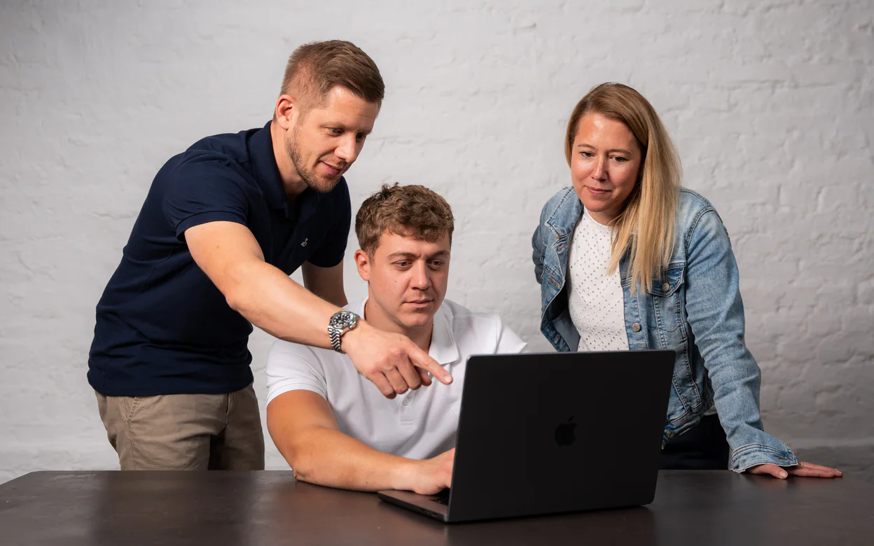 Drei Teammitglieder schauen gemeinsam auf einen Laptop