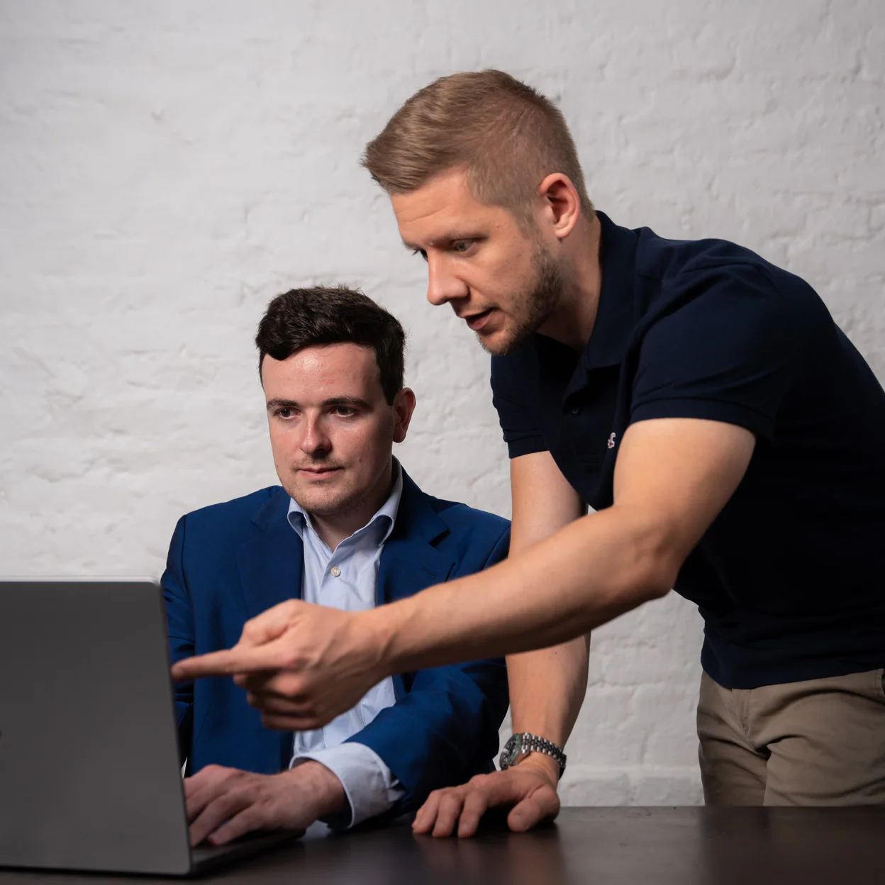 Ein Coach zeigt einem Kollegen etwas am Laptop