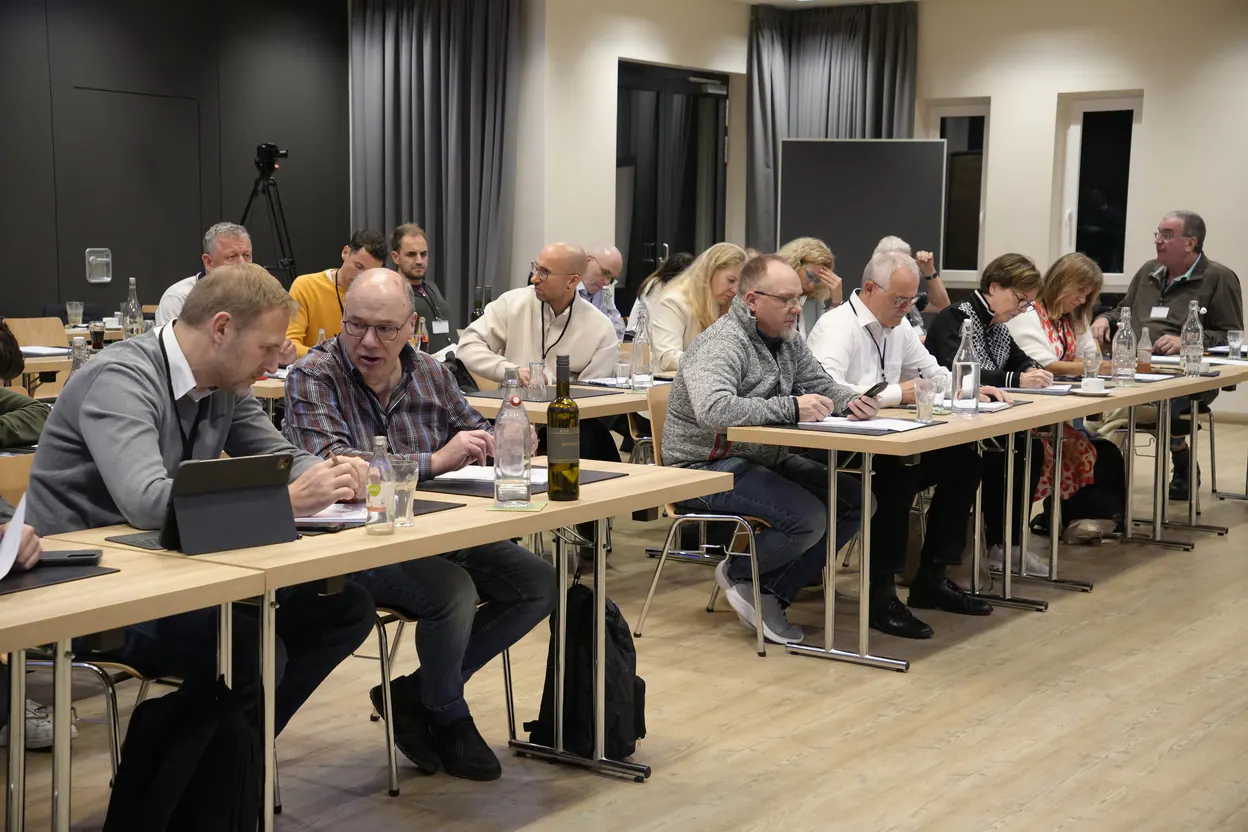 Teilnehmer eines Kundenevents der Legrand Investment GmbH an langen Tischen im Seminarraum