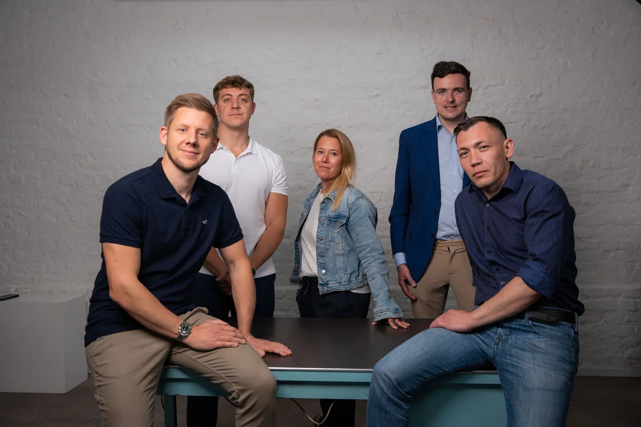 Fünf Kollegen der Legrand Investment GmbH sitzen entspannt an einem Tisch